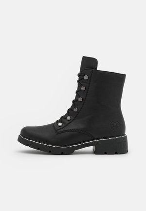 Bottines noires en cuir avec un bout rond, fermeture à lacets à l'avant, accents en métal argenté, semelle texturée et couture blanche contrastante.