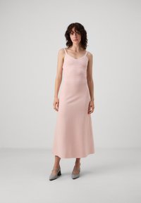 Abito midi rosa senza maniche con corpino aderente e gonna morbida. Realizzato in tessuto morbido, presenta una scollatura a V e dettagli a coste.