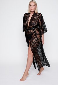 Zwarte kanten kimono-jas met bloemmotief, diepe V-hals, wijde mouwen en een satijnen riem. Heeft een hoge split en een gegolfde zoom.