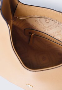 Světle hnědá kožená kabelka s vnitřkem z tkaniny s logem, zipovou kapsou a magnetickým uzavíráním.