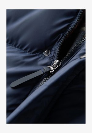 Marineblauwe pufferjack met een metalen rits, drukknoopsluiting en stoffen accenten. Gladde textuur met een gestikt patroon op het oppervlak.