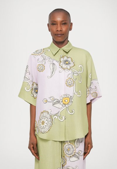 Short-sleeve button-up shirt featuring light green and lavender panels, floral patterns in yellow and black outlines, and a collared neckline.