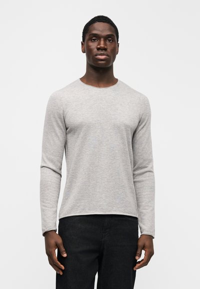 Ανοιχτό γκρι μακρυμάνικο πουκάμισο από απαλό ύφασμα, με στρογγυλή λαιμόκοψη και άνετη εφαρμογή. Συνδυασμένο με σκούρο τζιν.