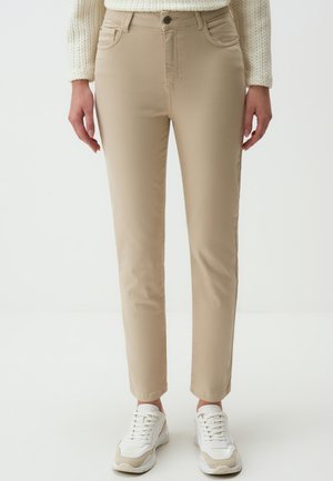 Pantaloni beige slim-fit in tessuto misto cotone con cinque tasche, passanti per cintura e chiusura con bottone. Indossati con sneakers bianche.
