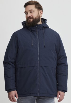 Veste à capuche bleu marine fabriquée dans un tissu léger et lisse, dotée d'une fermeture éclair à l'avant, de cordons de serrage et d'une coupe décontractée sans motifs visibles.