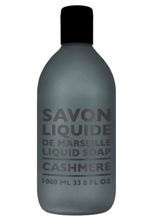 Bouteille de savon liquide en noir mat avec une forme arrondie. Présente un texte en relief : "Savon Liquide," "Cachemire," et des détails de volume en blanc.