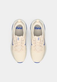 Hellebeige Sportschuhe mit einem Mesh-Obermaterial, blauen Akzenten und weißen Sohlen. Zu den Merkmalen gehören eine Schnürung und sichtbare "Air Zoom"-Markierung.