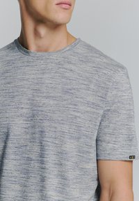 Lichtgrijs T-shirt met korte mouwen, van gemêleerd materiaal, met een ronde hals en een klein logoaccent op de linkermouw.