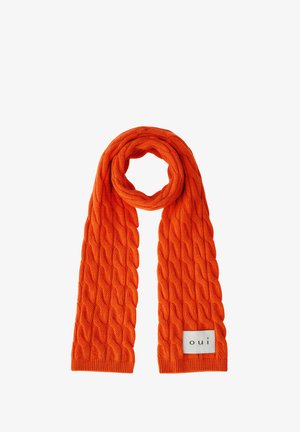 Orange gestrickter Kabelschal, zu einer Schlaufe gefaltet, mit einem weißen Etikett mit der Aufschrift "oui" am unteren Rand.