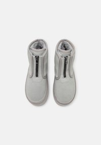 Bottes en daim gris avec fermeture éclair, doublure intérieure douce et bout arrondi. Caractéristiques d'une semelle texturée et de détails de couture.