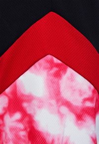 Färgglad textildesign med röda, svarta och rosa material. Inkluderar en mjuk, mönstrad struktur och kontrasterande kantdetaljer.