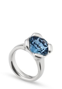 Bague en argent ornée d'une grande pierre bleue facettée, montée sur un anneau lisse et arrondi avec une finition polie et des accents courbés en forme de pétales.