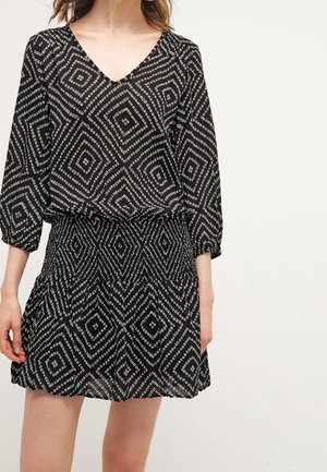 Zwarte met patronen jurk met een V-hals, 3/4 mouwen en een geraffineerde taille. Bevat witte geometrische diamantvormen over de stof.