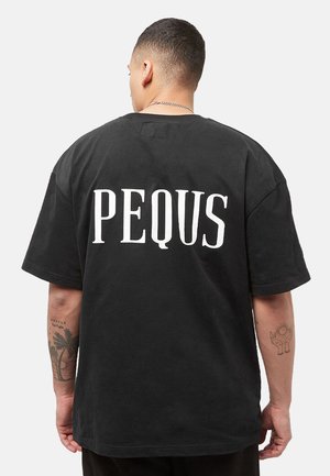 Man with short hair wearing black oversized t-shirt with large white text "PEQUS" on the back, shown from behind against a plain background.
