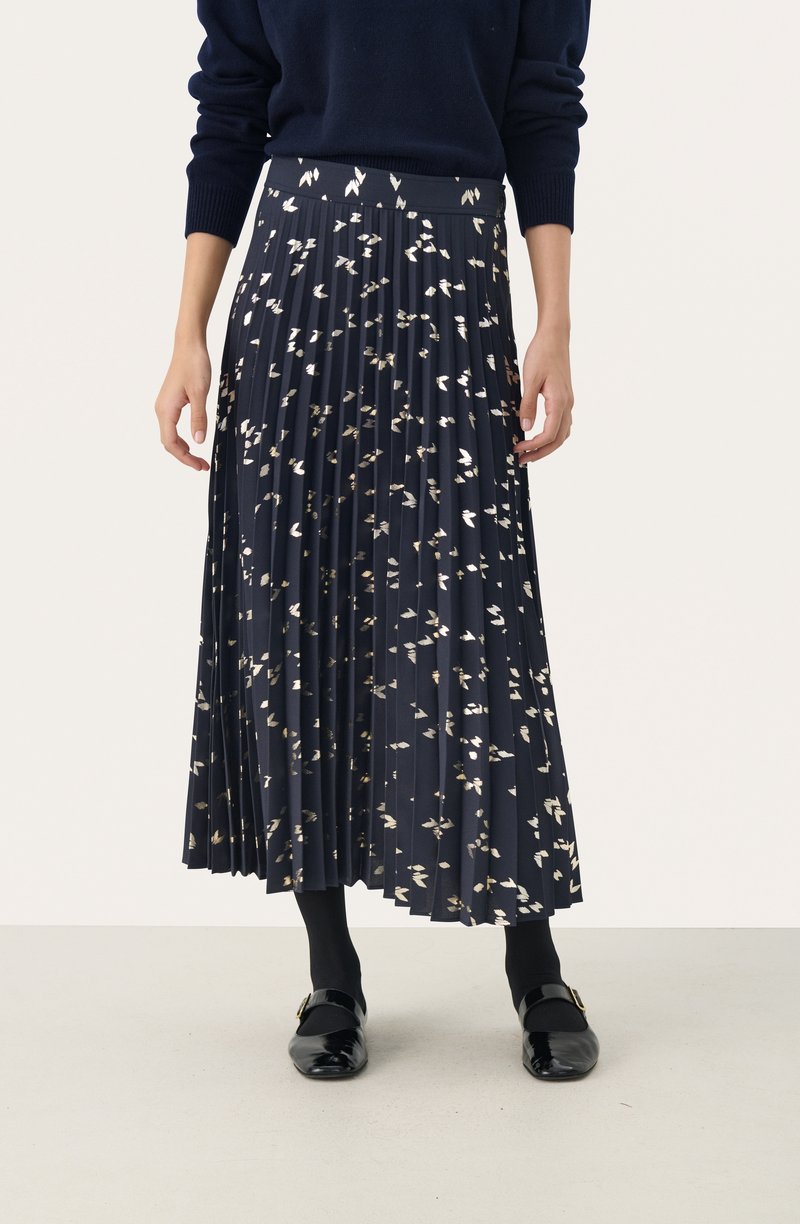 Jupe midi plissée en tissu bleu marine avec un imprimé de feuilles métalliques. Dotée d'une taille ajustée, elle tombe gracieusement jusqu'au milieu du mollet.