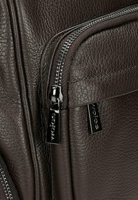 Borsa in pelle marrone con finitura testurizzata, doppie cerniere metalliche con tiranti logo e cuciture diritte a contrasto lungo le cuciture.