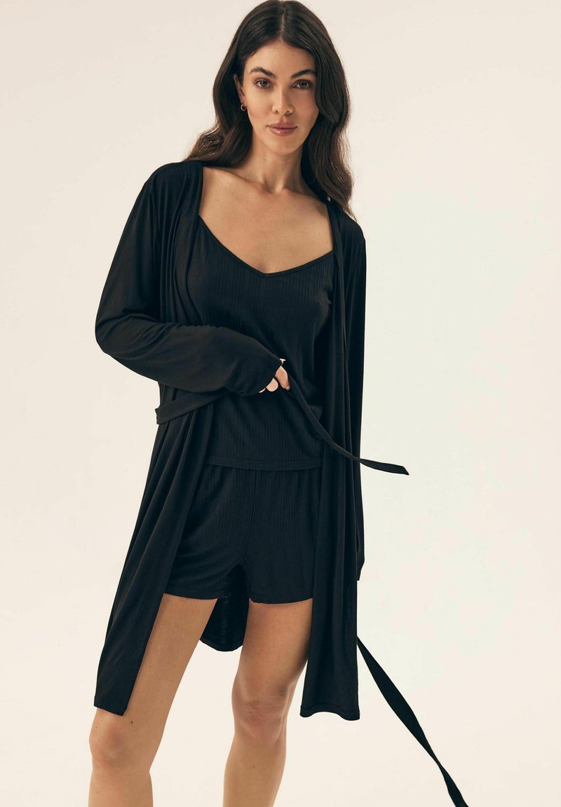 Czarny zestaw odzieży domowej składający się z długiego kardiganu z odkrytym przodem, prążkowanej bluzki na ramiączkach oraz szortów. Gładka tkanina, luźny krój i detal w postaci paska.