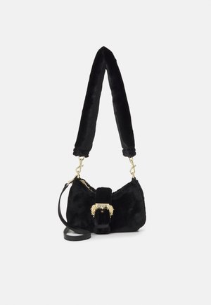 Sac à main en fausse fourrure noire avec large bandoulière, fermoir doré avec le logo "Versace Jeans Couture" et deux têtes de lion dorées.