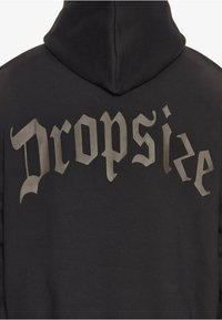 Schwarzer Kapuzenpullover mit einem großen, grauen, stilisierten "Dropsize"-Text auf dem Rücken. Hergestellt aus weichem Stoff mit einer zentralen Kapuze.