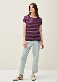 Lilla stribet T-shirt med rund halsudskæring og korte ærmer, parret med lyseblå vide denimbukser. Casual fodtøj fuldender outfittet.