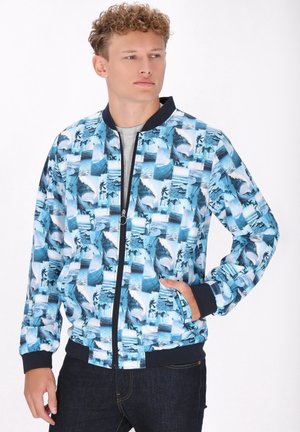 Bomberjack met een blauw-wit golf- en palmenpatroon, uitgerust met een ritssluiting, geribde manchetten en een marineblauwe kraag.