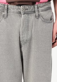 Grå denimjeans med rak benform, fem fickor och knappstängning. Tyget har ett subtilt strukturerat mönster.