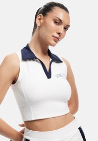 Witte mouwloze crop top met een marineblauwe kraag, met een subtiele logo-detail op de borst en een gladde, rekbare stof.