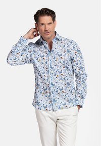 Chemise blanche à boutons avec un motif floral comportant des fleurs bleues, orange et jaunes, ainsi que des papillons ; manches longues avec des détails aux poignets.