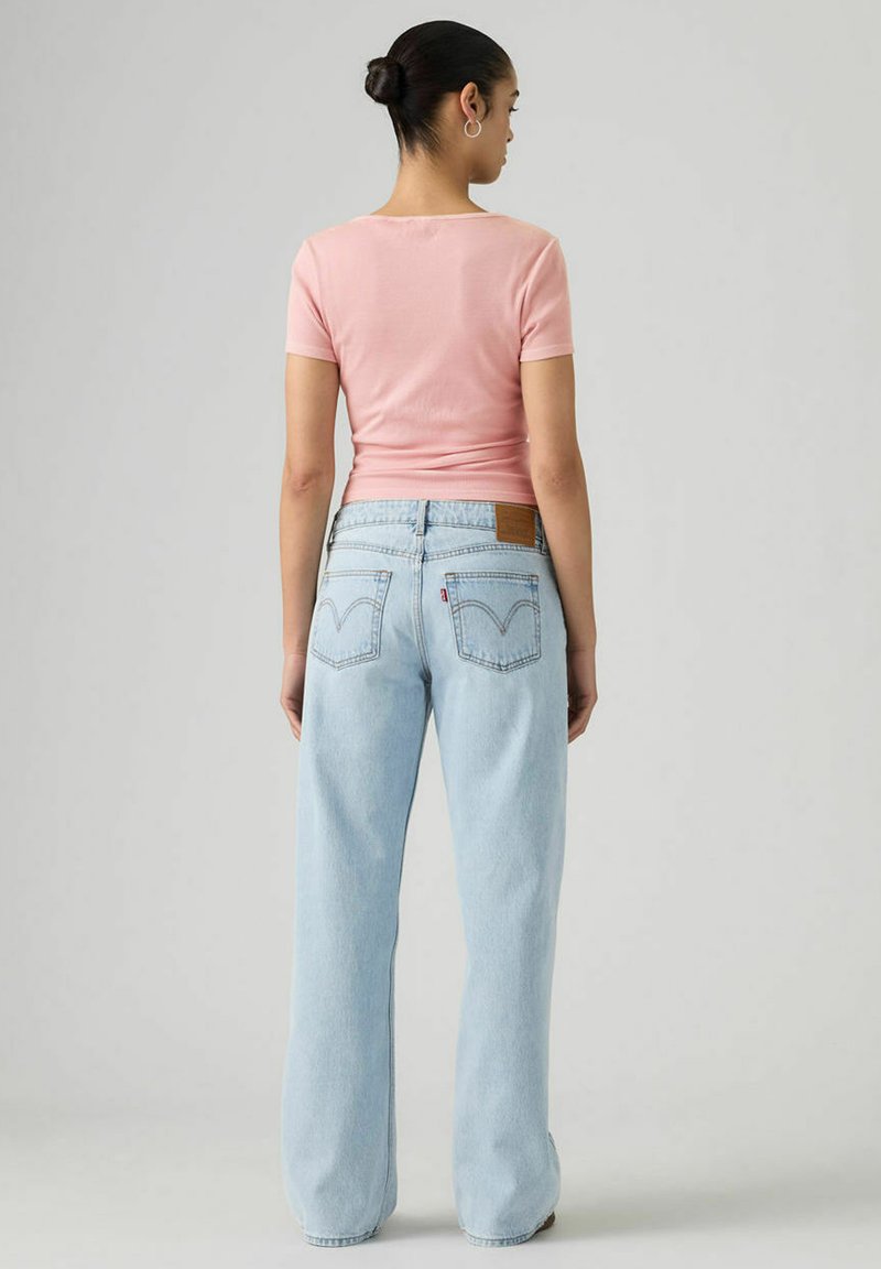 Light pink fitted t-shirt paired with loose light blue jeans featuring a brown leather label and classic back pocket stitching.