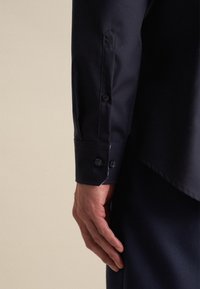 Marine dresshirt manchet met twee knopen, gemaakt van gladde stof. Beschikt over een puntsmanchet ontwerp met subtiele stikdetails.