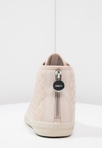 Beige vadstrumpa med kviltade detaljer och sidodragkedja, texturerad yta och gummisula. Har en logotypdetalj på dragkedjens dragare.