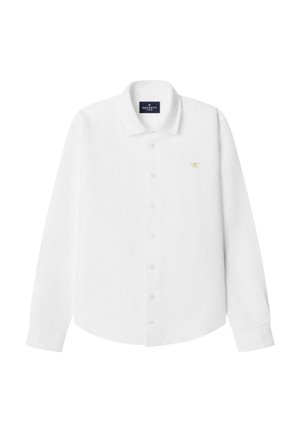 Camisa blanca de manga larga hecha de algodón, con cuello clásico, cierre de botones y un pequeño logo dorado en el pecho izquierdo.