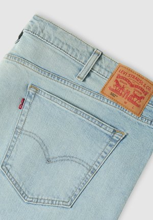 Lichtblauwe achterzak van Levi's spijkerbroek met kenmerkende rode tab en bruine leren merklabel waarop model 502 en stikdetails te zien zijn.