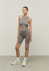 Szürke sportos cropped top és hozzá illő rövidnadrág, puha, rugalmas anyagból készült. Az öltözet varrás nélküli dizájnnal és testhez simuló siluettel rendelkezik.