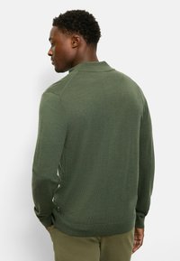 Grüner Baumwollpullover mit geripptem Kragen und Bündchen, ausgestattet mit einer strukturierten Oberfläche und einem slim fit Design. Die Rückansicht zeigt keine Muster oder Logos.