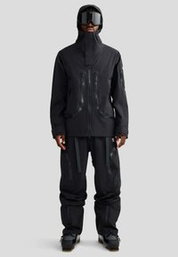 Czarny zestaw kurtki i spodni narciarskich, wyposażony w zamki błyskawiczne, wysoki kołnierz oraz liczne kieszenie. Wykonany z wodoodpornego materiału o nowoczesnym, eleganckim kroju.