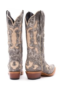 Stivali da cowboy in pelle grigia con elaborati ricami beige, punta affilata, bordi scallopati e un tacco marrone di media altezza.