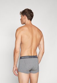 Boxer shorts in cotone grigio con una banda elastica scura che presenta il logo "Marc O’Polo". Texture liscia, design aderente, lunghezza a metà coscia.