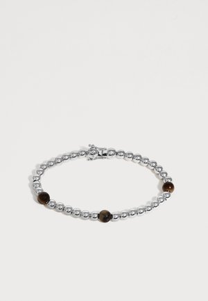 Bracelet perlé en argent avec trois grosses perles marron espacées uniformément et une petite fermeture sur un fond clair uni.