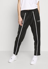 Svarta sweatpants med vita sidosträck, elastisk midja och snöre. Har Nike-logotypen i vitt på vänster lår.
