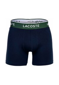 Boxer shorts blu navy con una fascia in logo Lacoste verde e bianca, realizzati in tessuto morbido con una texture liscia e un design aderente.