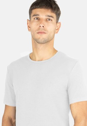 Weißes T-Shirt mit kurzen Ärmeln aus Baumwolle, mit rundem Halsausschnitt und dezentem gesticktem Logo auf der Brust. Glatte Textur.