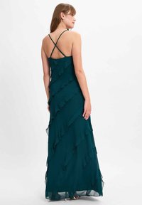 Türaux Maxi-Kleid mit geschichteten Rüschen, verstellbaren dünnen Trägern und einem fließenden Silhouette. Hergestellt aus leichtem, durchsichtigem Stoff mit einer weichen Textur.
