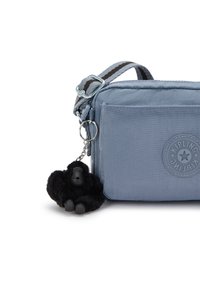 Borsa a spalla in tessuto blu con finitura testurizzata, dotata di un logo Kipling rotondo e un portachiavi a forma di gorilla nero.