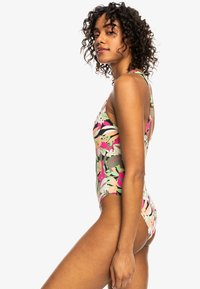 Maillot de bain une pièce à motif floral multicolore, avec un design dos nageur et un tissu lisse et extensible. Les accents incluent des teintes vertes, roses et beiges.