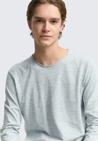 Jasnoniebieska koszula z długim rękawem, z okrągłym dekoltem, teksturowany materiał z subtelnym wzorem w paski i dopasowanymi rękawami.