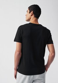 T-shirt nero a maniche corte in cotone. Presenta un collo rotondo e una vestibilità comoda, con una texture liscia e senza motivi visibili.