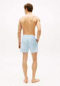 Pantaloni da bagno azzurri chiari realizzati in tessuto a asciugatura rapida, dotati di una cintura elastica, tasca posteriore e dettagli cuciti.