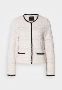 Cardigan bianco lavorato a maglia con bordi neri sul colletto, sulla parte anteriore, sui polsini e sui bordi delle tasche, caratterizzato da motivi geometrici testurizzati e bottoni frontali.