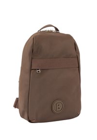 Brązowy plecak o gładkim, matowym wykończeniu, wyposażony w przedni pasek, okrągłe logo oraz zapięcie na zamek u góry.